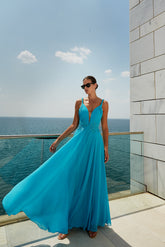 femme dans une robe bleue debout sur un balcon surplombant l’océan, robe fluide, longue robe bleue, robe fluide, robe bleu ciel, longue robe fluide luxueuse, robe en soie bleue, soie aqua fluide, portant une robe fluide